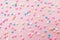 Pink,  white, yellow and blue  star shaped sprinkles on light pink background. Colourful edible cake decoration on pink background