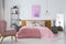 Pink woolen blanket and duvet on warm king size bed in classy bedroom interior, abstract painting on empty wall