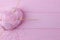 Pink woolen thread and wooden knitting needles on a pink background. Top view, free space