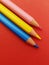 Pink, yellow and blue pencil over red table background. School starts soon!