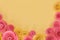 Pink and yellow rose flat lay background with crafted paper flowers at bottom and empty light yellow copy space