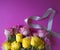 Pink and yellow roses and grey heart shape ribbon on pink background.