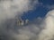 Pinnacle in the fog mountain peak under blue sky hides behind fog clouds