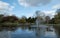 Pinner Memorial Park, Middlesex, UK taken on a sunny partially cloudy spring day, showing lake with fountain, birds, ducks