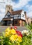 Pinner Parish Church in High Street, Pinner, UK with historic Tudor building in front. Colourful primula flowers in foreground.