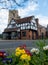 Pinner Parish Church in High Street, Pinner, UK with historic Tudor building in front. Colourful primula flowers in foreground.