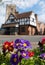 Pinner Parish Church in High Street, Pinner, UK with historic Tudor building in front. Colourful primula flowers in foreground.