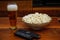 Pint of beer bowl of popcorn remote controllers and glasses on wooden background homemade entertainment