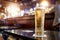 Pint glass of lager beer of cider on a table in bar in focus. Selective focus. Cinematic tone. Drinking after work concept. Enjoy