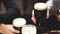 Pints of beer toast with two friends in a pub. Closeup mugs of draft root, light beer in male hands. Dark night scene.