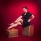 Pinup Girl in Black Dress Sits on Wooden Box