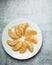Pinwheel of orange slices from  above on a white plate and concrete counter top peeled and ready to eat with room for text
