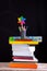 Pinwheel and pencils pot on stacked books, school supplies on white