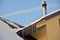 Pipe on the snow-covered roof with icicles of wooden house