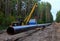 Pipelaying crane lowers a section of pipe into a trench. Construction of gas pipeline to new LNG plant. Crawler bulldozer with