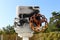 Pipeline with partially painted connection box and rusted metal valve at abandoned industrial complex surrounded with fence and