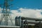 pipeline and power line support, in the photo pipeline and power line tower close-up against the background of blue sky and clouds