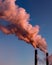 Pipes of a boiler room with thick pink smoke at sunset. Beautiful pink steam at dusk. Air pollution, environmental problems, air