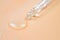 Pipette and liquid close-up on a peach-colored background, selective focus. Collagen, hyaluronic acid for skin care