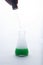 Pipette, pipet, medicine dropper above laboratory beaker with green liquid and smoke