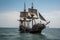 pirate ship, with sails unfurled and gunports ready to fire, on journey across the open sea