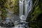 The Piroa waterfall cascading down the cliff face deep in the lush native bush and forest