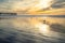 Pismo Beach sunset. Wide sandy beach with beautiful sun reflections, historical Pismo Beach pier, cloudy sky on background, birds.