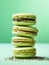Pistachio macarons on light turquoise background filled with chocolate and matcha powder cream. French pastry, matcha macaroons