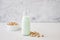 Pistachio milk in a bottle on a gray table next to pistachios. Plant milk
