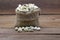 Pistachios in burlap sack on wooden background.