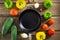 Pisto Manchego traditional Spanish dish. Cast iron frying pan among multi-colored vegetables on a wooden background