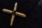 Pistol bullets gathered together in the shape of a cross. War concept. Dark background shot
