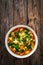 Pistou soup Nice - broth with basil pesto, noodles and vegetables on wooden background in white bowl