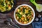 Pistou soup Nice - broth with basil pesto, noodles and vegetables on wooden background in white bowl