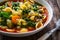 Pistou soup Nice - broth with basil pesto, noodles and vegetables on wooden background in white bowl