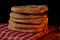 Pita breads stacked on a rustic cloth and a cutting board on a wooden table with black background with soft candle light