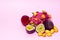 Pitahaya, tamarillo, kumquat and passion fruit cut in half on pink background
