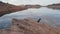 Pitbull dog in a warm fleece jacket is sitting on a sandstone cliff