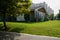 Pitch-roofed building on roadside lawn in city of sunny summer m