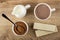 Pitcher with milk, cup of cocoa with milk, cocoa with sugar, spoon in bowl,  wafers with porous chocolate on table. Top view