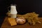 Pitcher of milk, round rye bread, a sheaf of wheat, bread slices on a wooden table