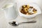 Pitcher with yogurt, cereal breakfasts with yogurt in bowl, spoon on wooden table