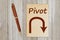 Pivot message with arrow on old paper notepad with a pen