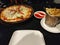 Pizza alongside Fries and sauce. Empty plates, Chilly flakes and Olive oil on the background