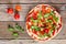 Pizza with arugula and cherry tomatoes against rustic wood