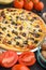 Pizza on a black background with ingredients, tomatoes, salami, mushrooms, sauce and mazzarella cheese.Italian pizza, the concept
