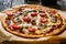 Pizza with champignons, ham, tomatoes, olives, parmesan and mozzarella on wooden background