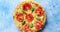 Pizza with cheese and tomatoes on blue stone table