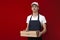 Pizza delivery man in uniform on a red background gives a ready order, the courier guy holds pizza boxes