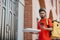 Pizza delivery. Serious delivery man with helmet, with backpack holding box and looking at smartphone, near front door